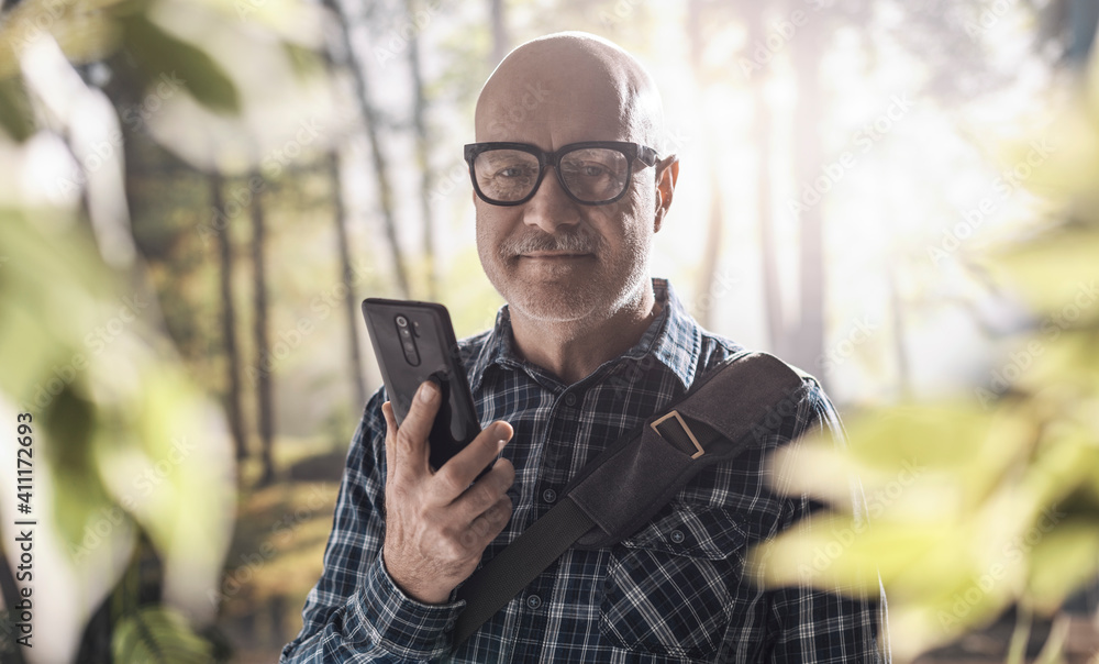 Happy man connecting in the forest with his smartphone Happy man connecting in the forest with his smartphone