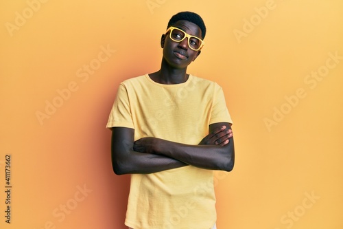 Young african american man wearing casual clothes and glasses smiling looking to the side and staring away thinking. © Krakenimages.com