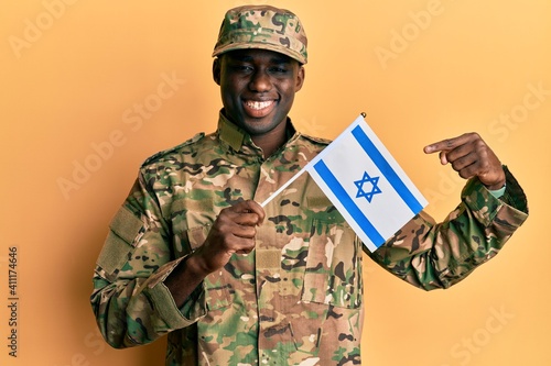Young african american man wearing army uniform holding israel flag smiling happy pointing with hand and finger