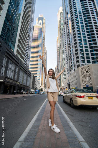 Young casual woman walk with raised hands enjoy the view on downtown skycrapers.