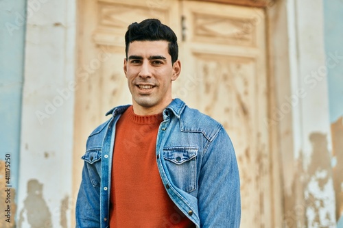 Young hispanic man smiling happy standing at the city.