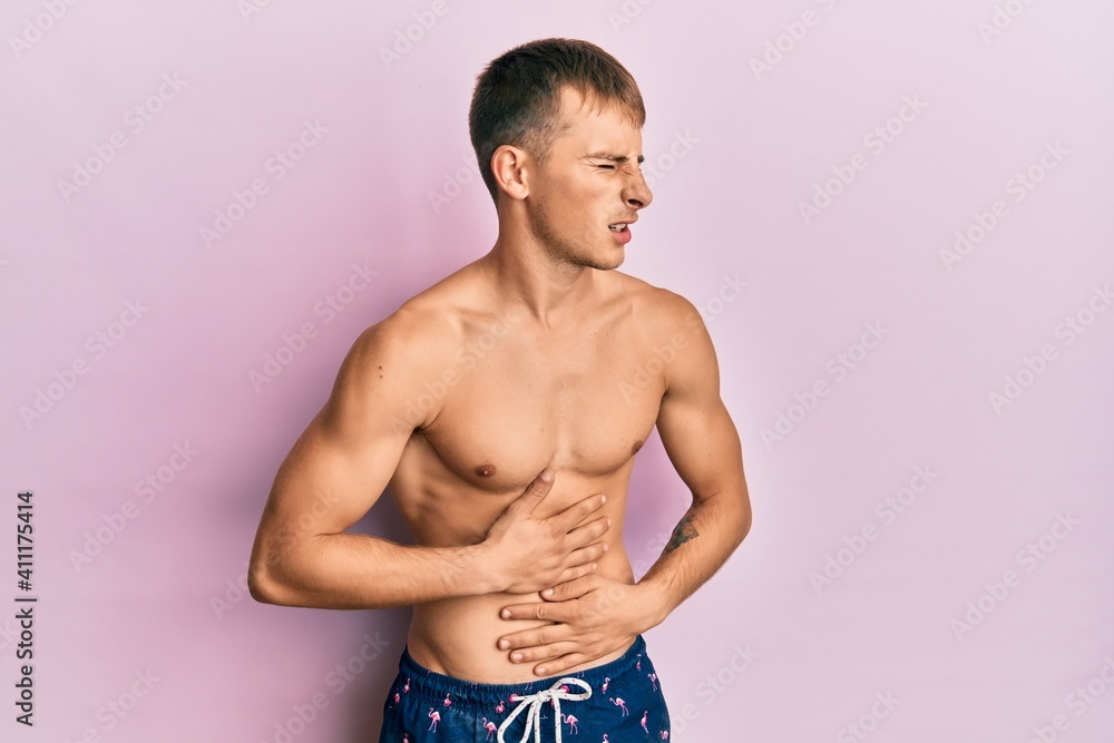 Fototapeta premium Young caucasian man wearing swimwear with hand on stomach because nausea, painful disease feeling unwell. ache concept.
