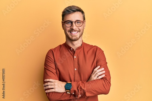 Handsome caucasian man wearing casual clothes and glasses happy face smiling with crossed arms looking at the camera. positive person. photo