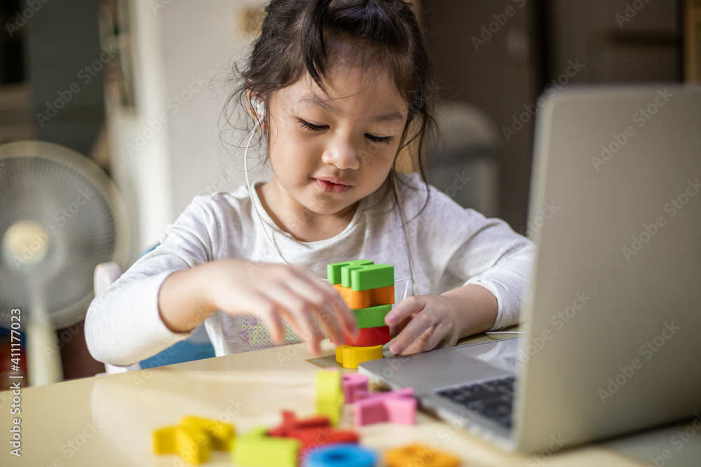 Asian girl learning alphabets online, Happy girl learn online with laptop at home. New normal. Covid-19 coronavirus. Social distancing. stay home Asian girl learning alphabets online, Happy girl learn online with laptop at home. New normal. Covid-19 coronavirus. Social distancing. stay home