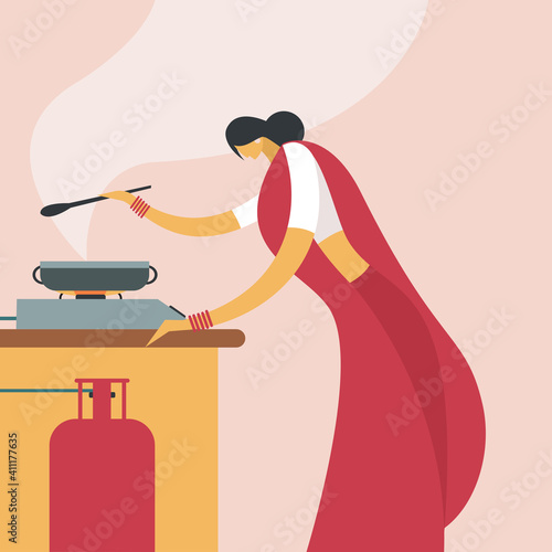 A woman wearing 'Sari' cooking in a kitchen using gas stove