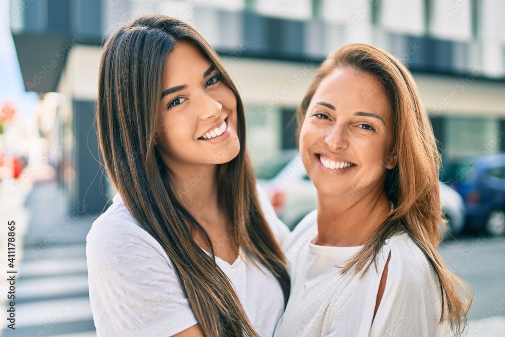 Fototapeta premium Beautiful hispanic mother and daughter smiling happy standing at the city.