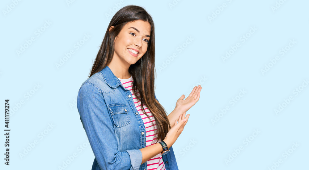 Young brunette woman wearing casual clothes inviting to enter smiling natural with open hand Young brunette woman wearing casual clothes inviting to enter smiling natural with open hand