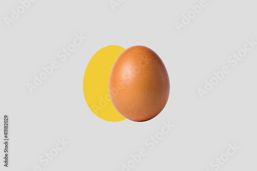 Chicken egg on a creative background. Yellow silhouette of an egg on a gray background. Egg on a yellow oval