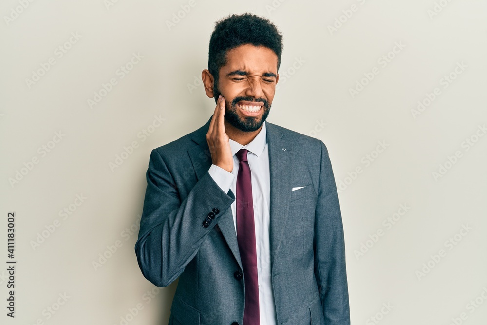 Handsome hispanic man with beard wearing business suit and tie touching mouth with hand with painful expression because of toothache or dental illness on teeth. dentist Handsome hispanic man with beard wearing business suit and tie touching mouth with hand with painful expression because of toothache or dental illness on teeth. dentist