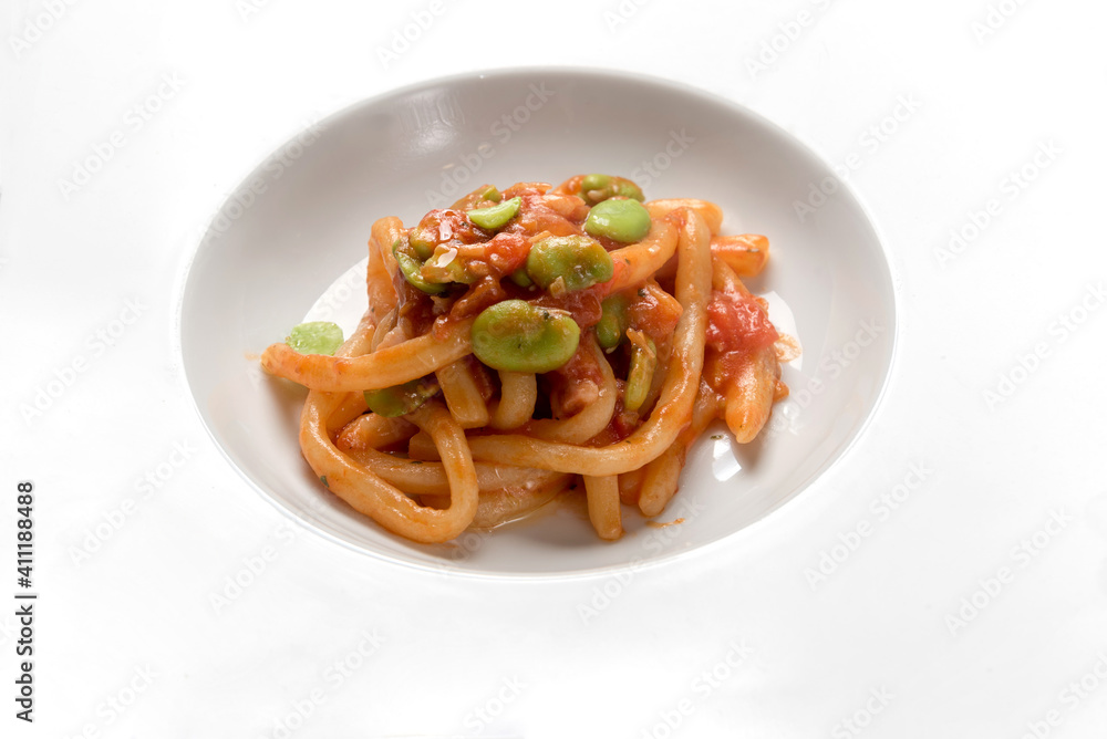 Pici and fave, italian hand rolled pasta with tomato sauce and broad beans, close up and text space on white Pici and fave, italian hand rolled pasta with tomato sauce and broad beans, close up and text space on white