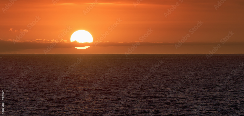 Sun is setting on horizon at sunset sunrise over sea or ocean. Tranquil sea ocean waves