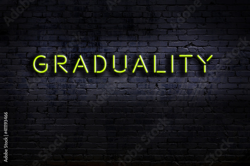 Night view of neon sign on brick wall with inscription graduality photo