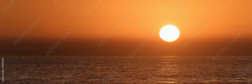 Sun is setting on horizon at sunset sunrise over sea or ocean. Tranquil sea ocean waves
