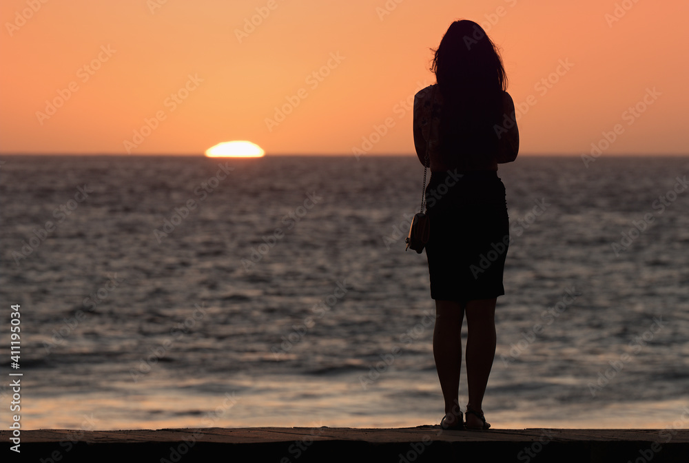 Silhouette of sensual woman watching sunset at the beach