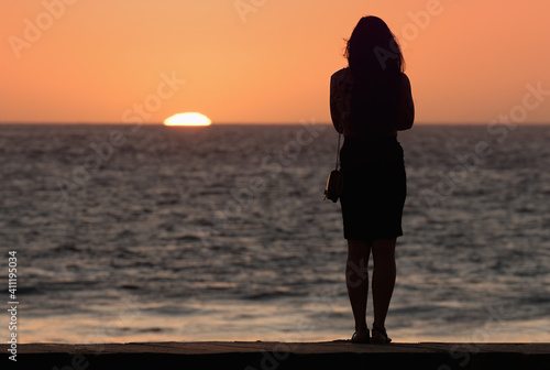 Silhouette of sensual woman watching sunset at the beach