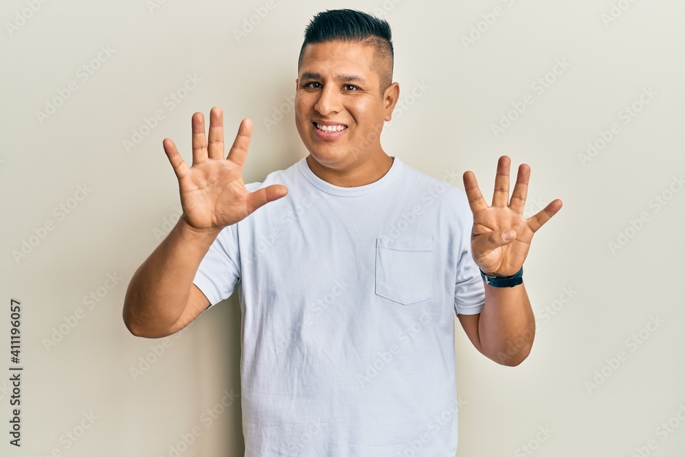Young latin man wearing casual white t shirt showing and pointing up with fingers number nine while smiling confident and happy. Young latin man wearing casual white t shirt showing and pointing up with fingers number nine while smiling confident and happy.