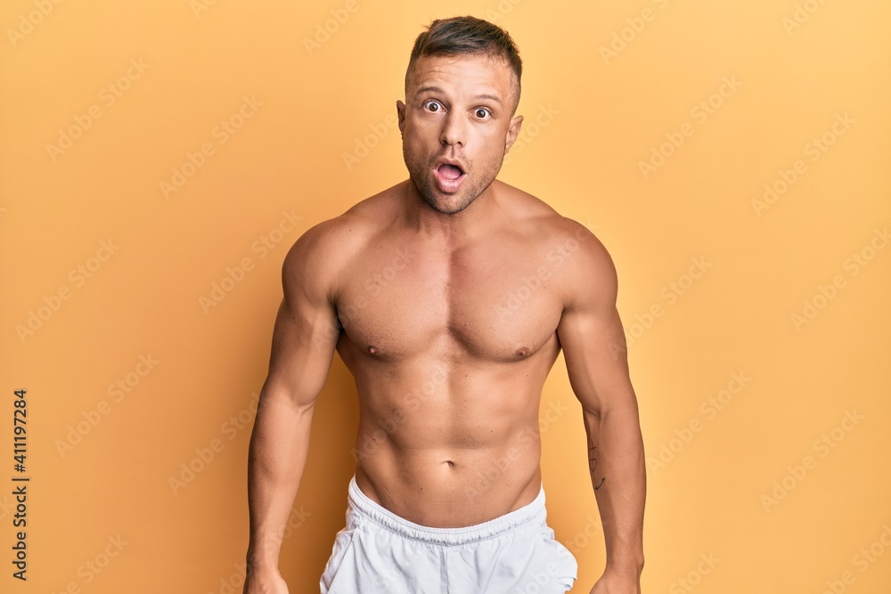 Fototapeta premium Handsome muscle man standing shirtless scared and amazed with open mouth for surprise, disbelief face