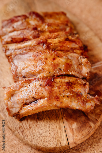 fried with spices pork ribs in a glass baking sheet on a wooden cutting board. cooked meat at home. Barbecue.