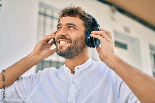 Handsome man with beard wearing headphones and enjoying listening to music outdoors