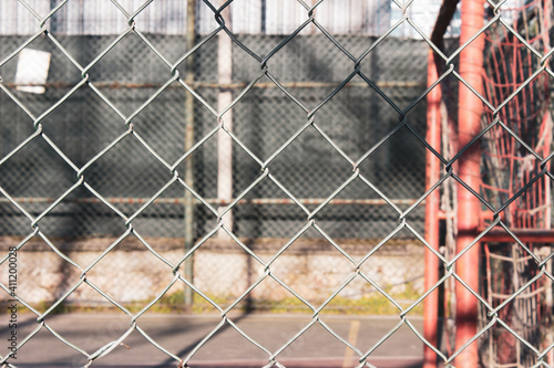 Sports arena behind the fences. Selective focus on rusty fences in front of the basketball court.