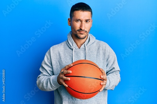 Handsome man with tattoos holding basketball ball skeptic and nervous, frowning upset because of problem. negative person. © Krakenimages.com