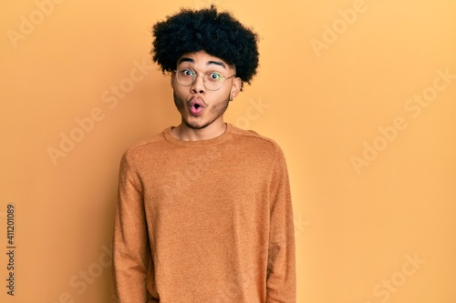 Young african american man with afro hair wearing casual winter sweater afraid and shocked with surprise expression, fear and excited face. © Krakenimages.com