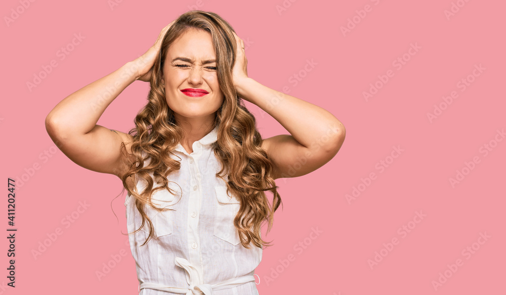 Young blonde girl wearing casual clothes suffering from headache desperate and stressed because pain and migraine. hands on head. Young blonde girl wearing casual clothes suffering from headache desperate and stressed because pain and migraine. hands on head.