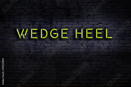 Night view of neon sign on brick wall with inscription wedge heel photo