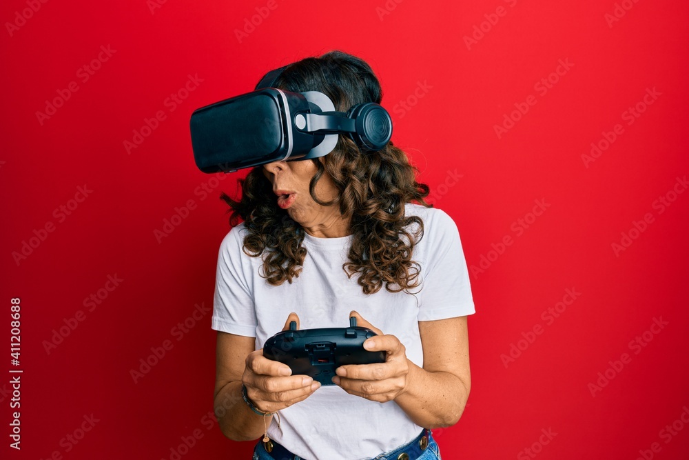 Middle age woman wearing virtual reality glasses playing 3D videogames, watching futuristic simulation, excited experience Middle age woman wearing virtual reality glasses playing 3D videogames, watching futuristic simulation, excited experience