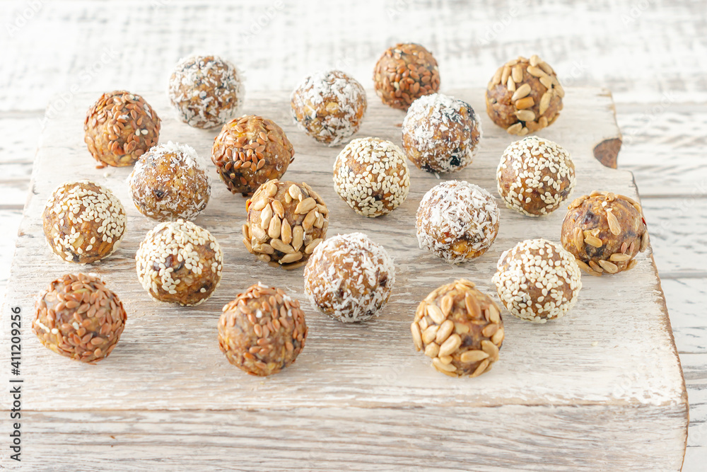 Vegan healthy energy balls with oatmeal, chia seed, coconut flakes, cocoa, dried fruits and almond. No cook energy bites on white wooden desk. Vegan healthy energy balls with oatmeal, chia seed, coconut flakes, cocoa, dried fruits and almond. No cook energy bites on white wooden desk.