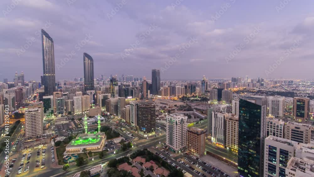 Modern city architecture of Abu Dhabi skyline day to night transition aerial timelapse, UAE. Illuminated skyscrapers and traffic on the road. Abu Dhabi is the capital and the second most populous city Modern city architecture of Abu Dhabi skyline day to night transition aerial timelapse, UAE. Illuminated skyscrapers and traffic on the road. Abu Dhabi is the capital and the second most populous city