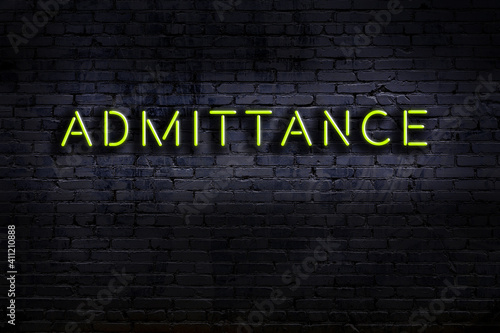 Neon sign. Word admittance against brick wall. Night view