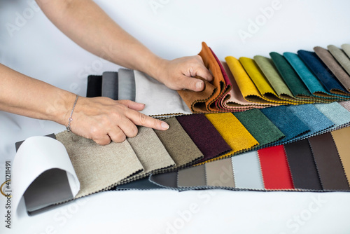 Fotografie Women's hands point to a light brown fabric in the fabric catalog for upholstered furniture