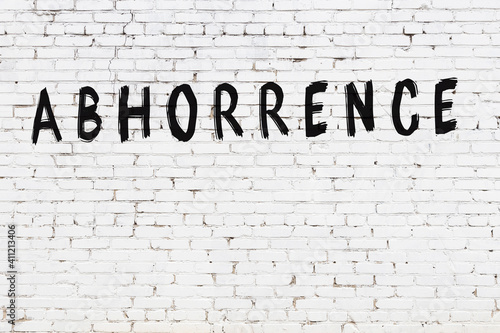 Inscription abhorrence painted on white brick wall