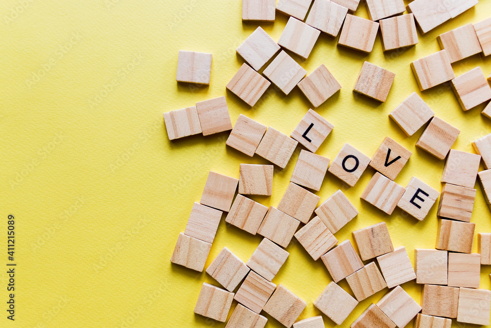 Pile of wooden letters on the surface of a yellow background with spell love, valentine's day. Selective focus