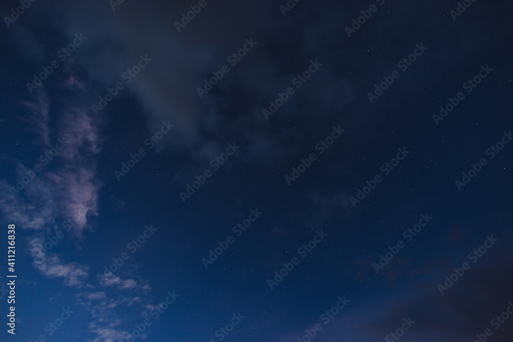 Stars in the night sky through the clouds on a summer night