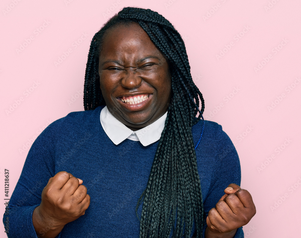 Young black woman with braids wearing casual clothes excited for success with arms raised and eyes closed celebrating victory smiling. winner concept. Young black woman with braids wearing casual clothes excited for success with arms raised and eyes closed celebrating victory smiling. winner concept.