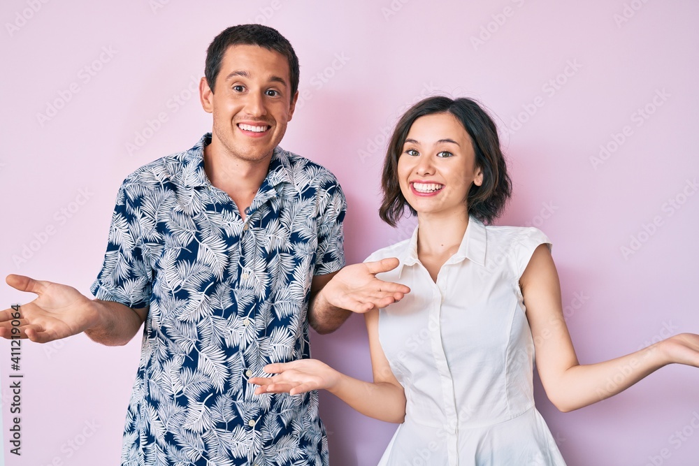 Beautiful couple wearing casual clothes smiling showing both hands open palms, presenting and advertising comparison and balance Beautiful couple wearing casual clothes smiling showing both hands open palms, presenting and advertising comparison and balance