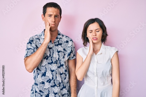Beautiful couple wearing casual clothes touching mouth with hand with painful expression because of toothache or dental illness on teeth. dentist