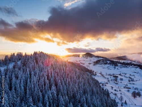 Rolling Clouds At Dense Spruce Coniferous Forest On Snowy White Hill Slope In Winter During Sunset. - Aerial Drone Shot. A forest Densely Covered With Fresh Snow