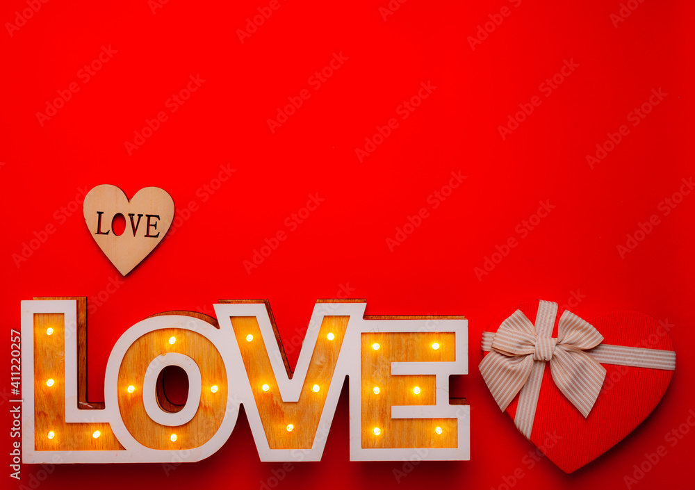 gift box in the form of a heart and the inscription love from wooden letters on a red background
