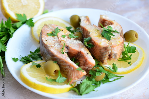 roasted fish with lemon olives and parsley on the beige background