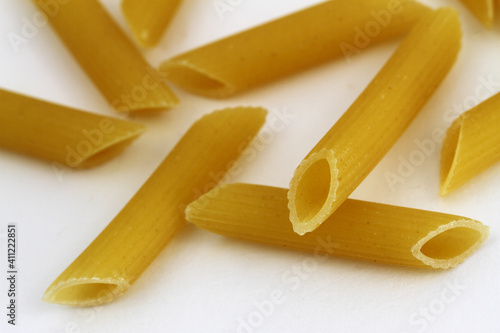 Uncooked Italian pasta, penne rigate on white surface, closeup 