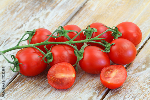 Sweet, ripe and juicy cherry tomatoes on stem on rustic wooden surface 