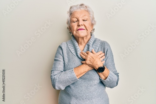 Senior grey-haired woman wearing casual clothes smiling with hands on chest, eyes closed with grateful gesture on face. health concept.