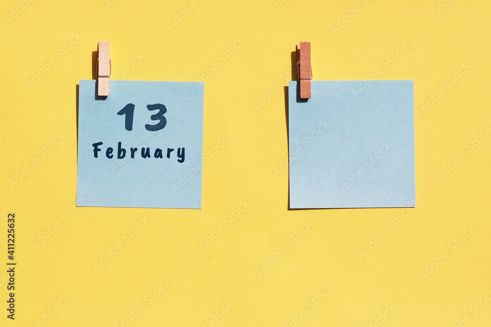 13st of February. 13st day of the month, calendar date. Two blue sheets for writing on a yellow background. Top view, copy space. Winter month, day of the year concept 13st of February. 13st day of the month, calendar date. Two blue sheets for writing on a yellow background. Top view, copy space. Winter month, day of the year concept