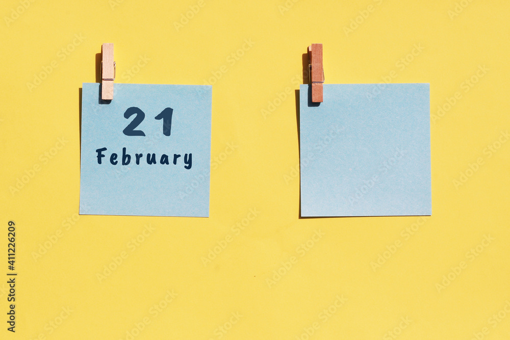 21st of February. 21st day of the month, calendar date. Two blue sheets for writing on a yellow background. Top view, copy space. Winter month, day of the year concept 21st of February. 21st day of the month, calendar date. Two blue sheets for writing on a yellow background. Top view, copy space. Winter month, day of the year concept