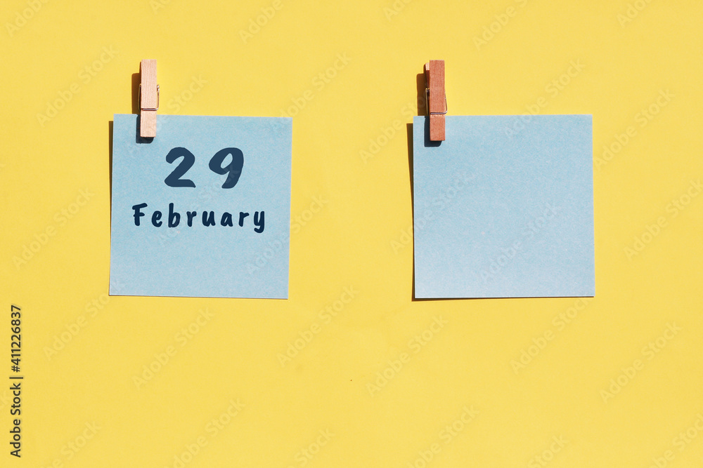 29st of February. 29st day of the month, calendar date. Two blue sheets for writing on a yellow background. Top view, copy space. Winter month, day of the year concept 29st of February. 29st day of the month, calendar date. Two blue sheets for writing on a yellow background. Top view, copy space. Winter month, day of the year concept