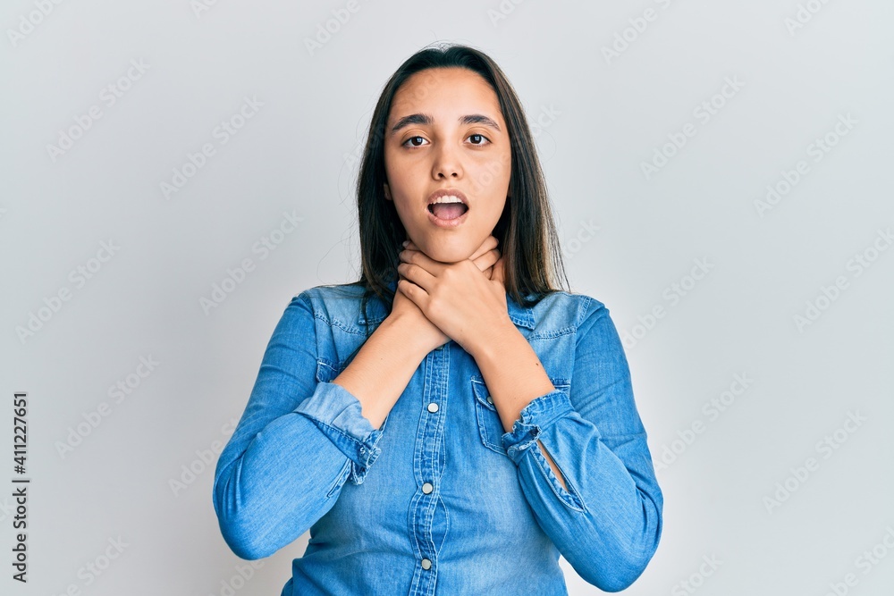 Young hispanic woman wearing casual denim jacket shouting and suffocate because painful strangle. health problem. asphyxiate and suicide concept. Young hispanic woman wearing casual denim jacket shouting and suffocate because painful strangle. health problem. asphyxiate and suicide concept.