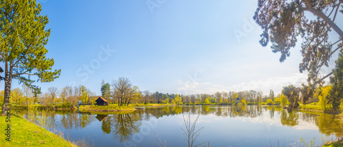 Panoramic view over city park and lake in Spring colors at sunny day with blue sky, Magdeburg, Germany.